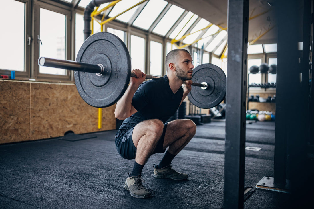An athlete performing a deep barbell back squat in a weight room