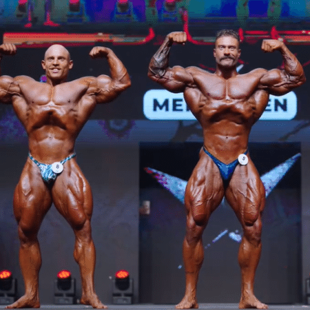 Chris Bumstead and Martin Fitzwater standing side by side in front double biceps poses at the 2024 Prague Pro