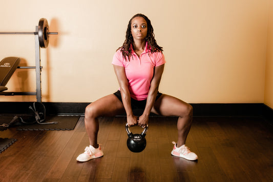 Athlete holding a kettlebell between the legs during a wide-stance sumo squat