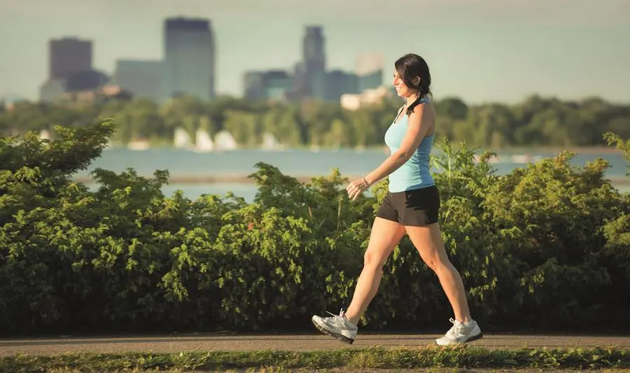 A woman walking briskly beside a lake in daylight