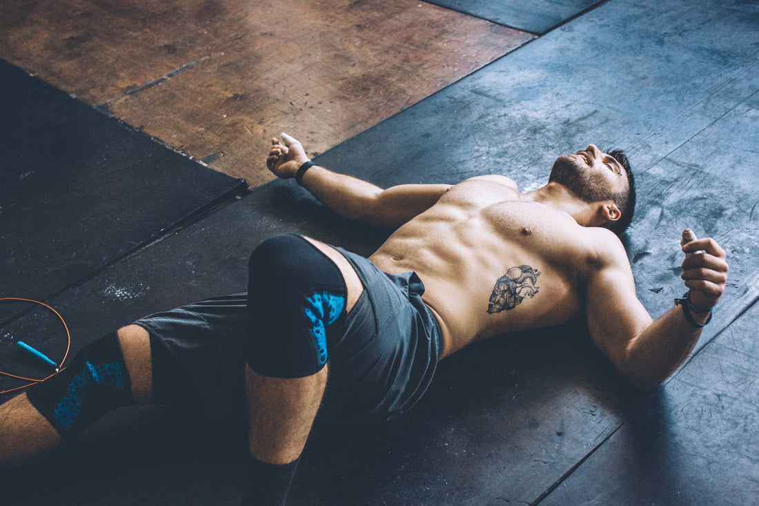 Muscular athlete lying on his back on a gym floor after training, resting with arms relaxed