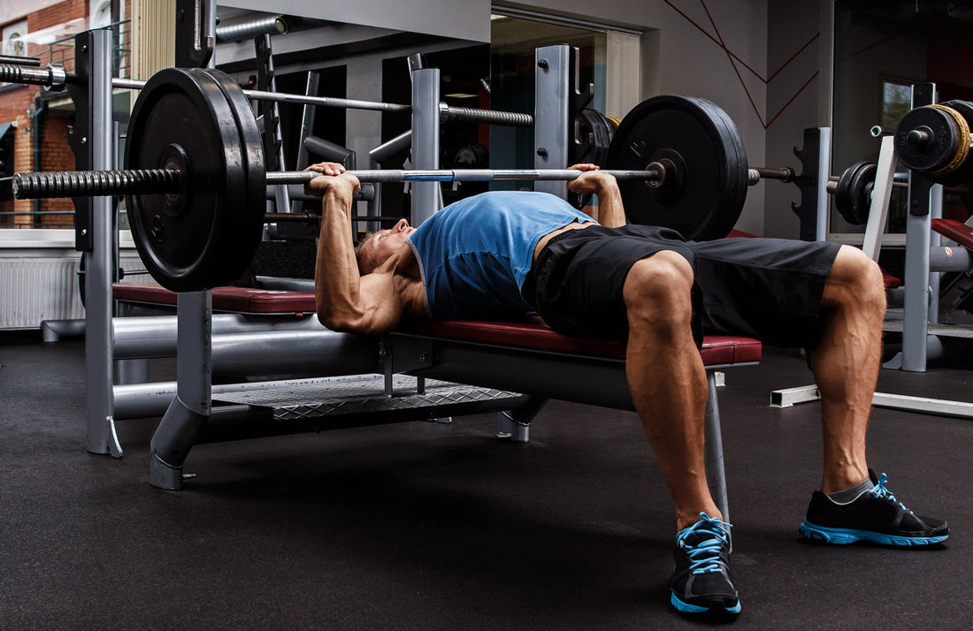 Powerlifter performing a controlled barbell bench press in a gym