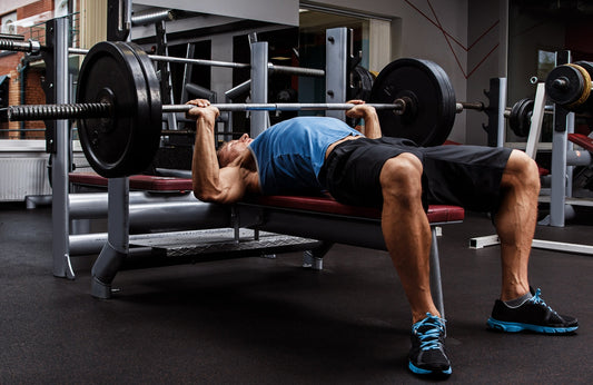 Powerlifter performing a controlled barbell bench press in a gym