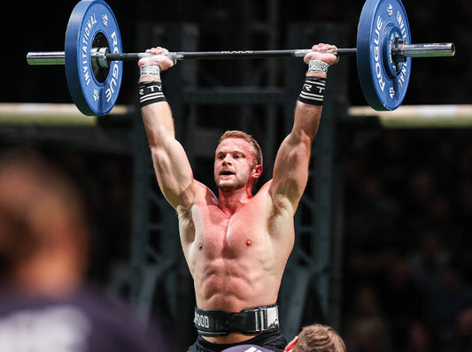 Dallin Pepper lifting a loaded barbell overhead on the competition floor at a major CrossFit event