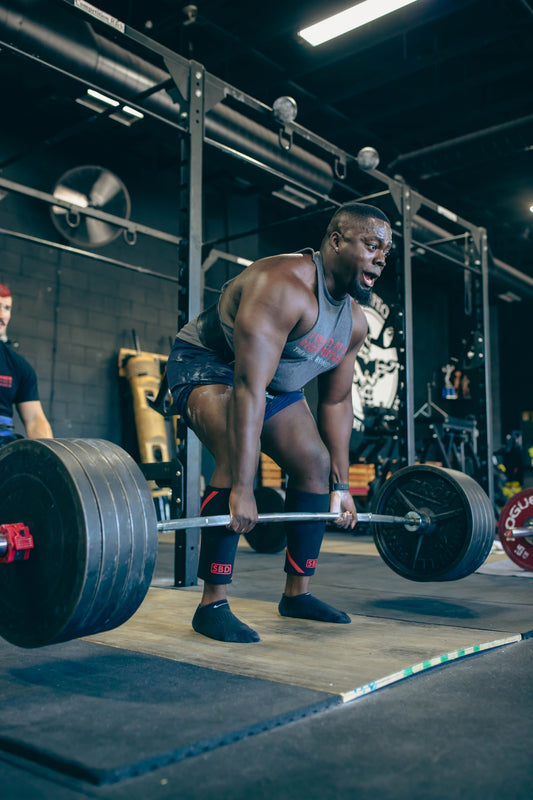 Muscular strength athlete performing a heavy deadlift with a loaded barbell