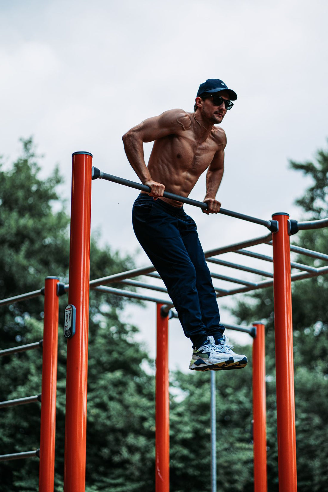 Athletic man using an outdoor pull-up bar during a bodyweight strength session