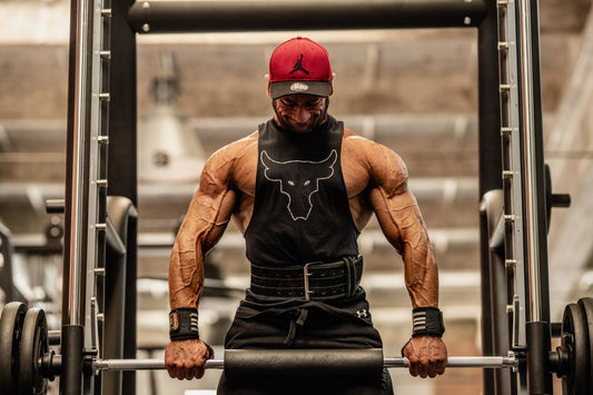 Muscular male bodybuilder lifting a barbell in a gym