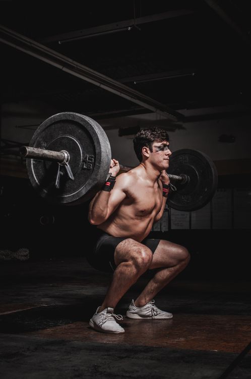Superman-inspired athlete performing a controlled heavy squat in a power rack