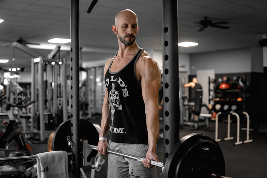 Middle-aged male lifter performing heavy compound barbell training in a gym