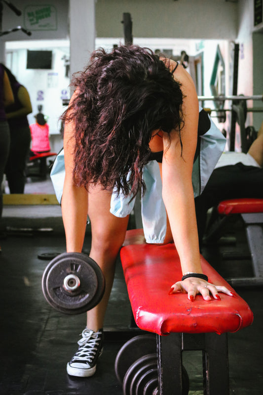 Woman strength training with dumbbells in a gym