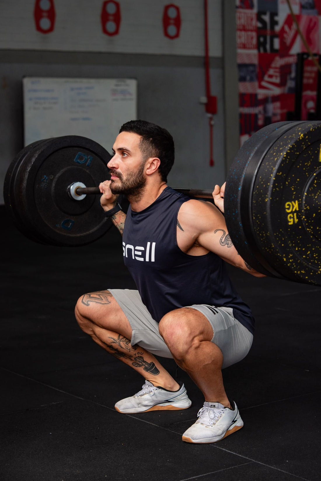 Male athlete performing a heavy barbell back squat inside a gym