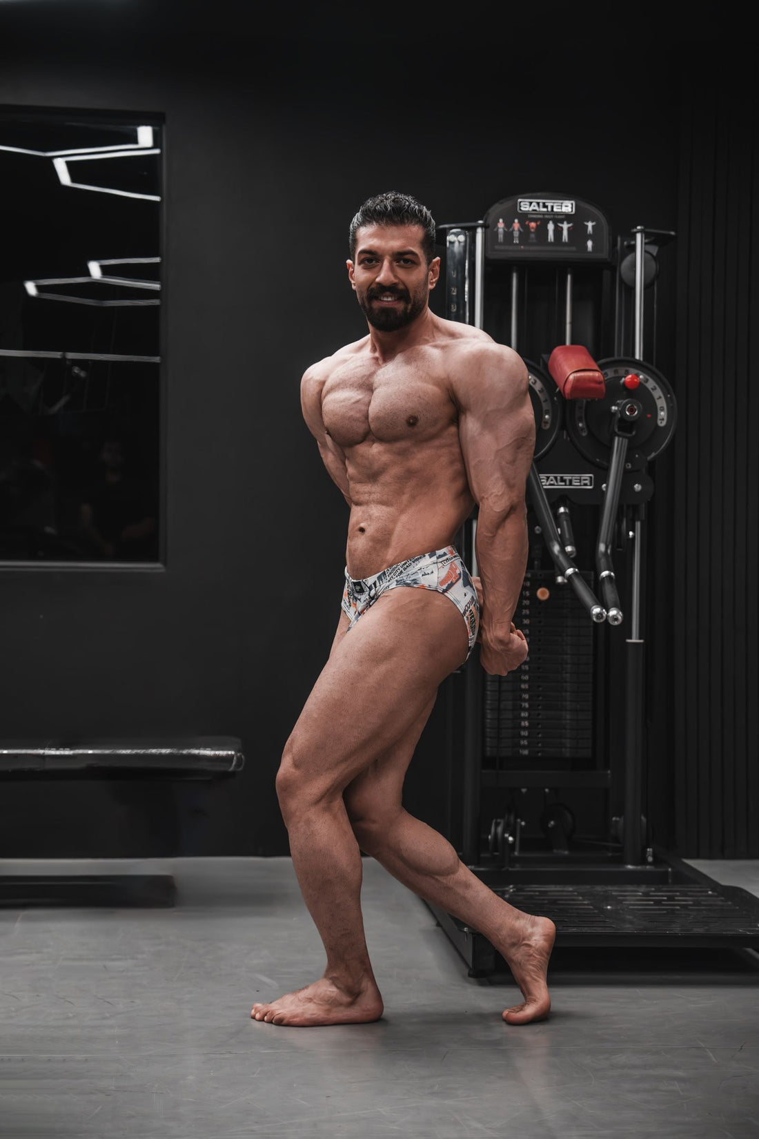 Bodybuilder posing in a gym and displaying developed muscular physique