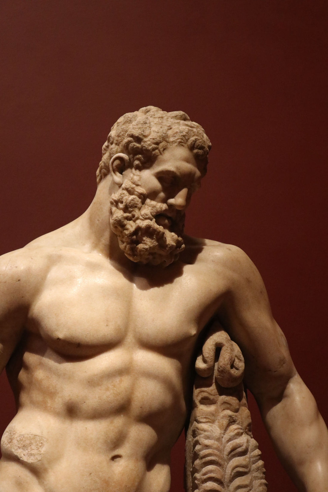 Ancient Greek marble statue of a muscular hero with defined shoulders and torso