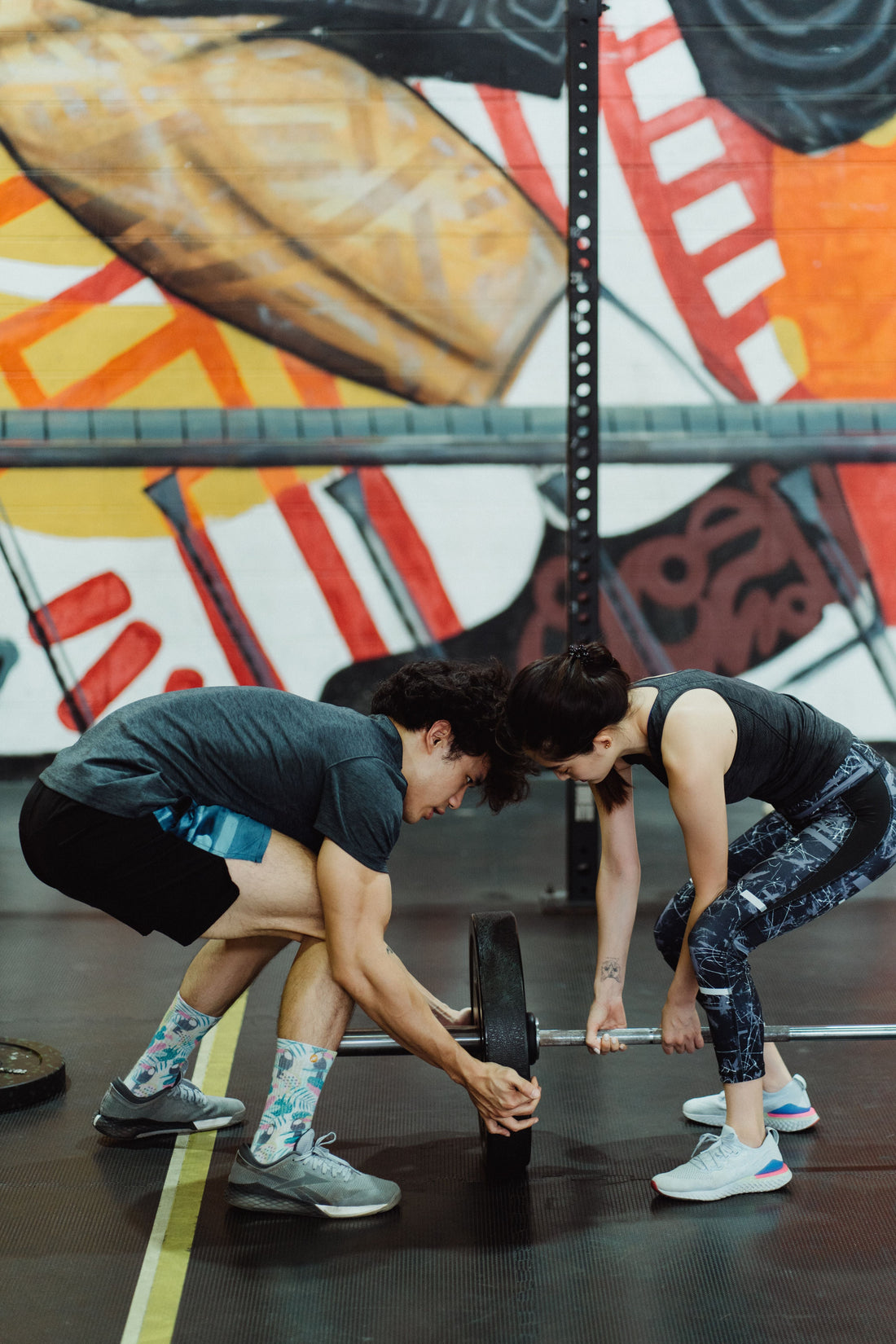 Man and woman performing barbell squats together in a gym