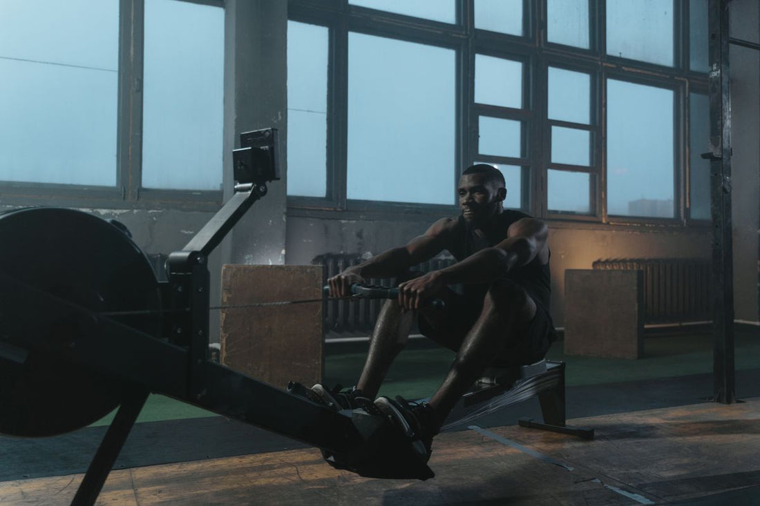 Muscular athlete training on an indoor rowing ergometer in a gym