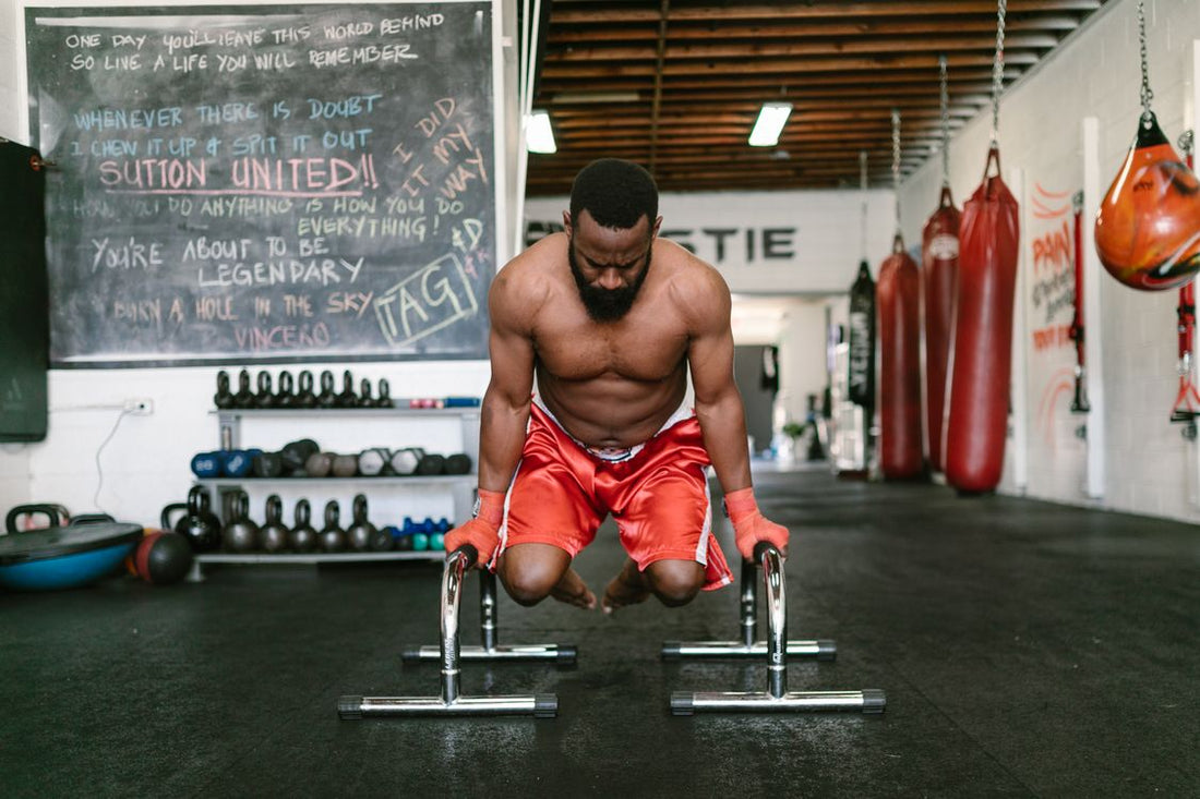 Calisthenics athlete practicing a demanding bodyweight exercise on parallel bars in a gym