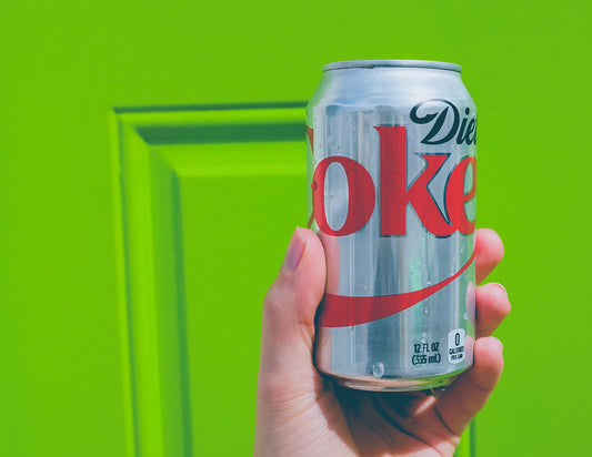 Silver diet cola can against a green background