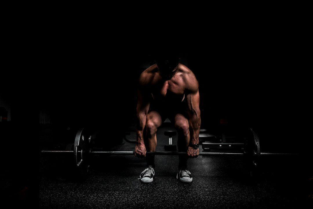 Illustrative gym photograph of a muscular athlete training with weights