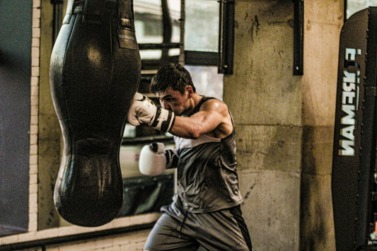 Boxer wearing white gloves punches a heavy bag inside an industrial gym