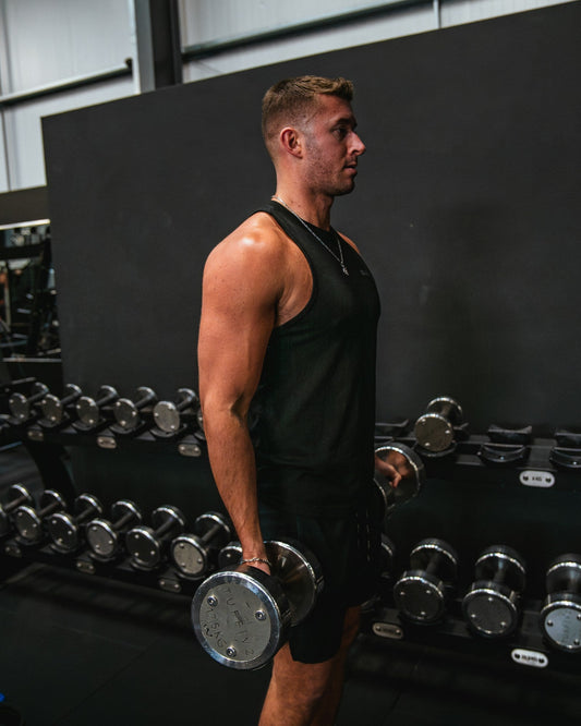Muscular man training his biceps with dumbbells in a gym