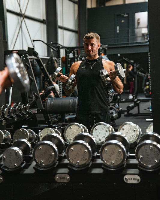 Muscular lifter training with dumbbells in a gym; no text or graphics