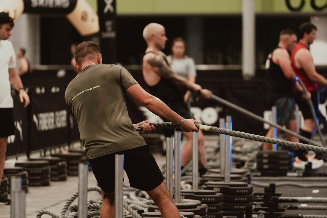 Competitor performing a standing hand-over-hand rope pull on a loaded HYROX-style sled