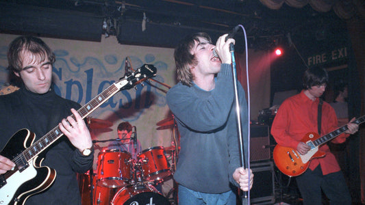 Oasis playing live in an intimate club with Liam Gallagher singing and Bonehead playing guitar