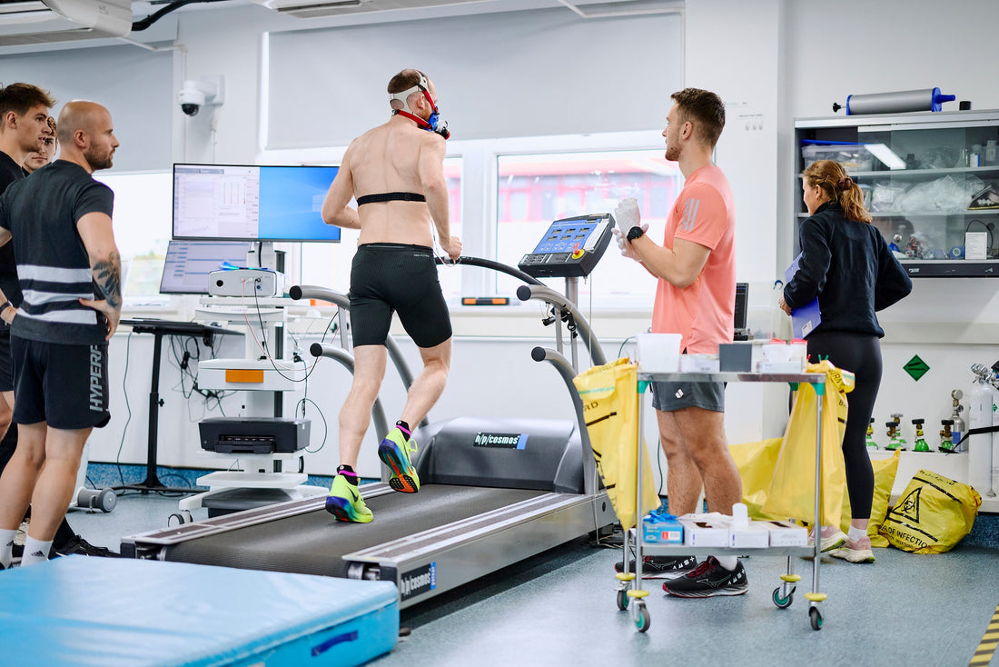 Sports scientists monitoring an athlete running on a treadmill during exercise physiology testing