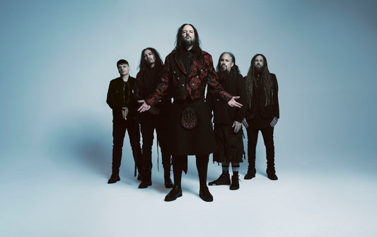 Korn band members in a studio group portrait with Jonathan Davis at center against a pale backdrop.
