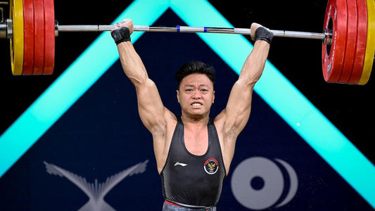 Indonesian weightlifter Rahmat Erwin Abdullah holding a loaded barbell overhead on the Ningbo 2026 competition platform
