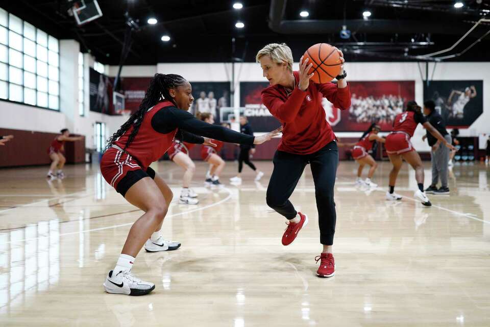 Women basketball players practicing defensive movement in yellow uniforms on an indoor court