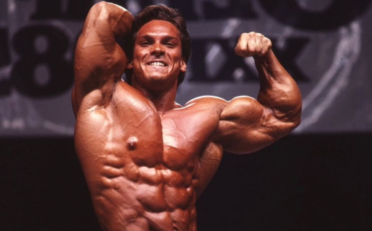 Vintage stage photograph of Rich Gaspari flexing during a bodybuilding competition; no text overlay
