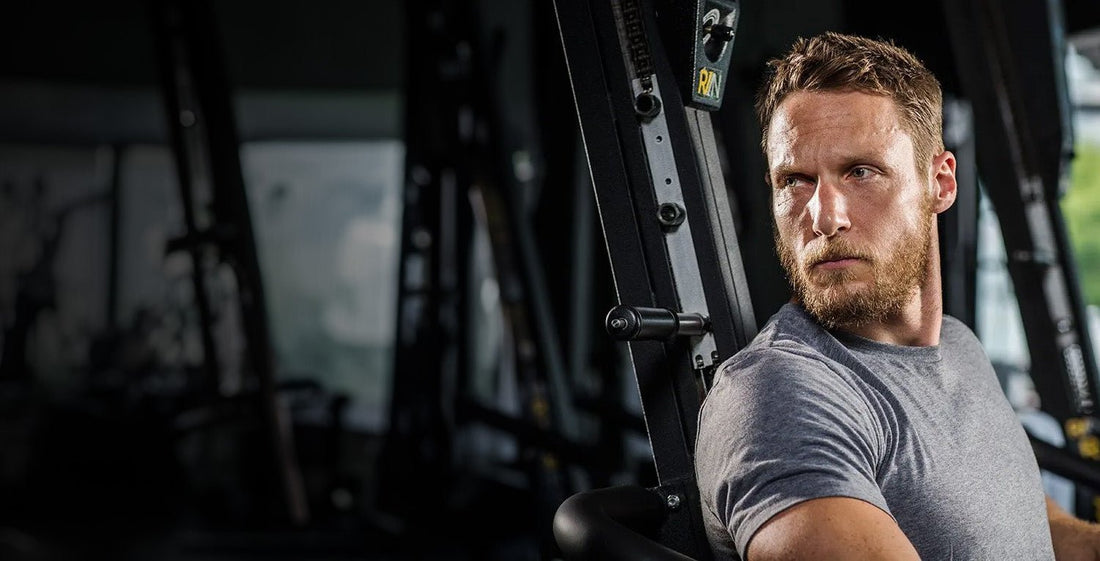 Celebrity strength coach Jason Walsh seated beside a weight-training machine inside a gym