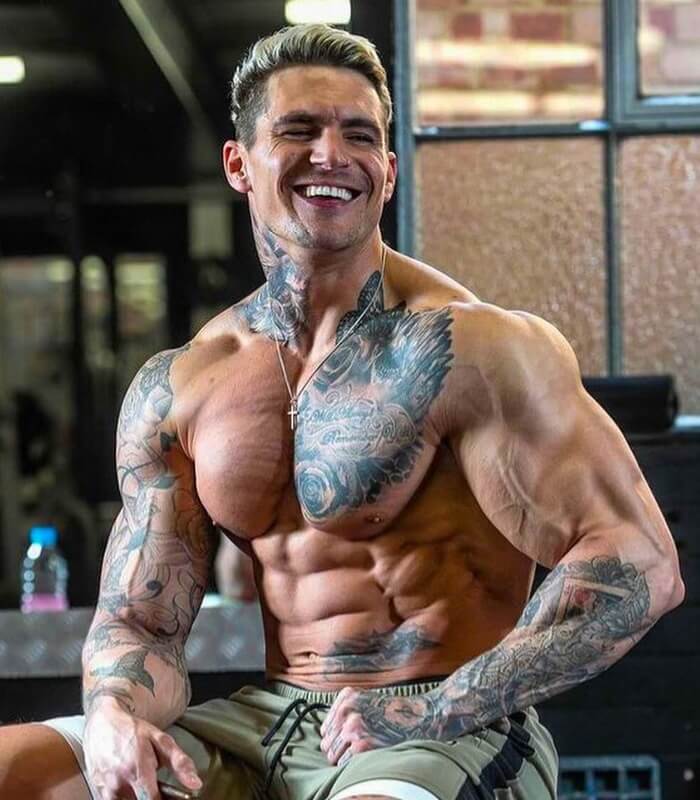 Ross Dickerson smiling in a gym, with defined chest and shoulders