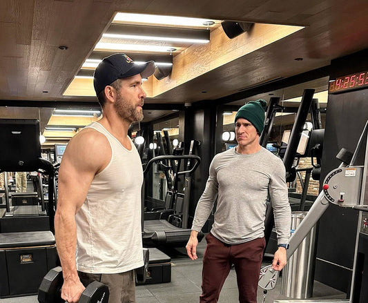 Ryan Reynolds training with Don Saladino in a gym while holding dumbbells