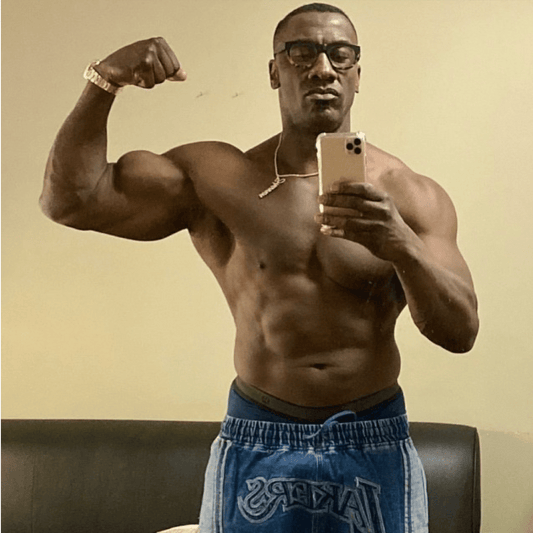 Shannon Sharpe flexing one large biceps in a shirtless mirror selfie