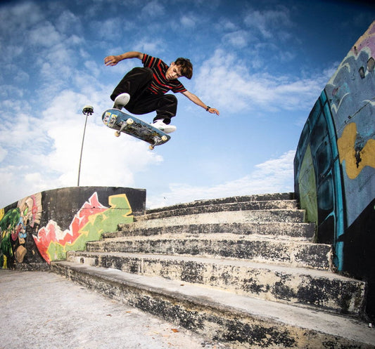 Skateboarder jumping over stairs while controlling body position above the board
