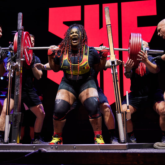 Sonita Muluh performing a heavily loaded raw back squat on a powerlifting competition platform