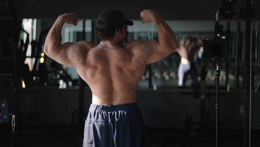 Sam Sulek flexing his back and arms in a rear double-biceps gym pose