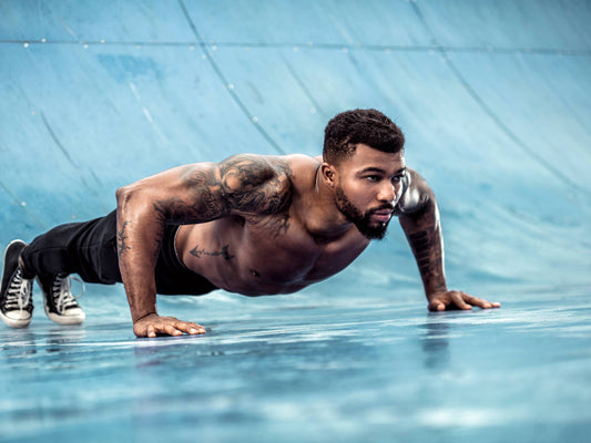 Muscular athlete performing a strict floor push-up on a blue training surface