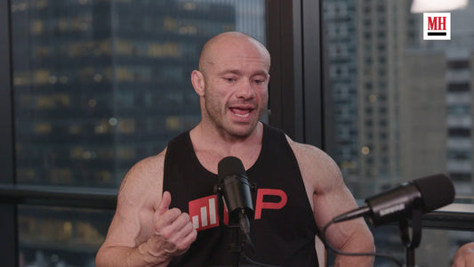 Mike Israetel speaking in a studio wearing a black Renaissance Periodization training shirt
