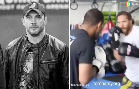 Tom Hardy in Bane-era training style with heavy dumbbells and an industrial gym backdrop