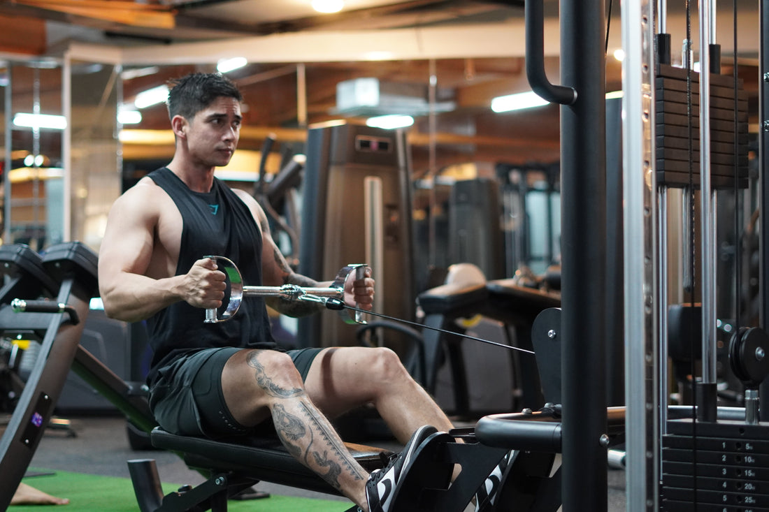 Gym athlete seated at a cable row station pulling a neutral-grip handle toward the abdomen