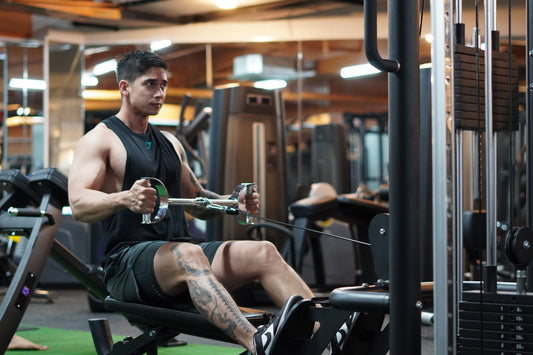 Gym athlete seated at a cable row station pulling a neutral-grip handle toward the abdomen