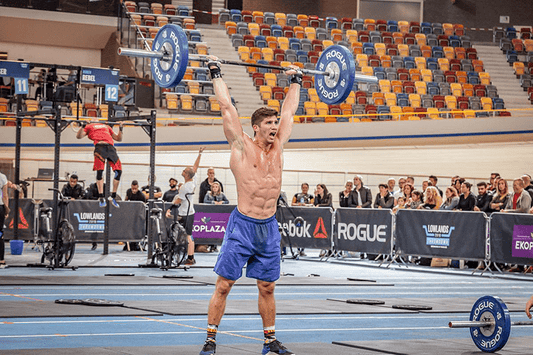 CrossFit athlete locking out a barbell thruster overhead