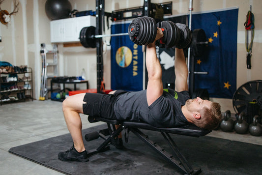 Lifter pressing adjustable dumbbells in a home gym