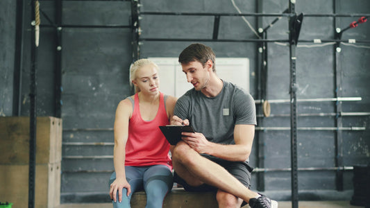 Personal trainer and client reviewing training progress together in a gym