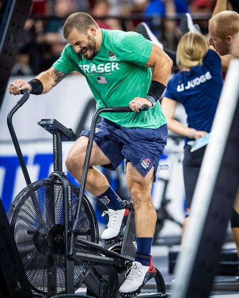 Elite CrossFit athlete sprinting on an Assault Bike during competition