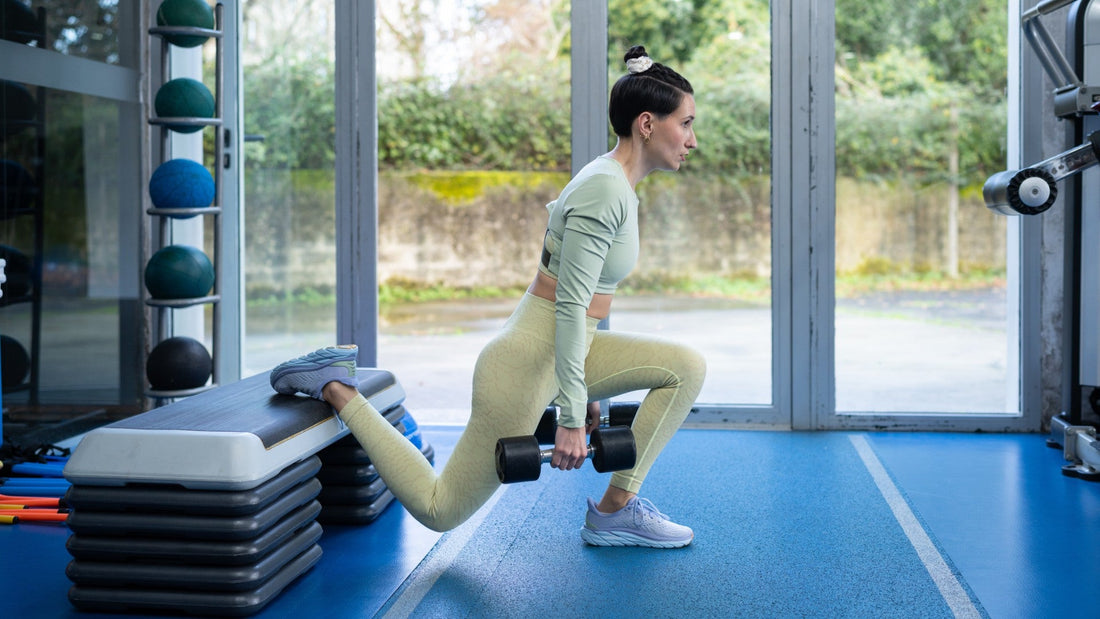 athlete performing a controlled dumbbell Bulgarian split squat in a gym
