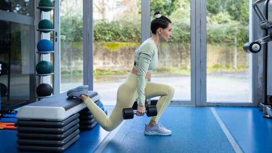 athlete performing a controlled dumbbell Bulgarian split squat in a gym